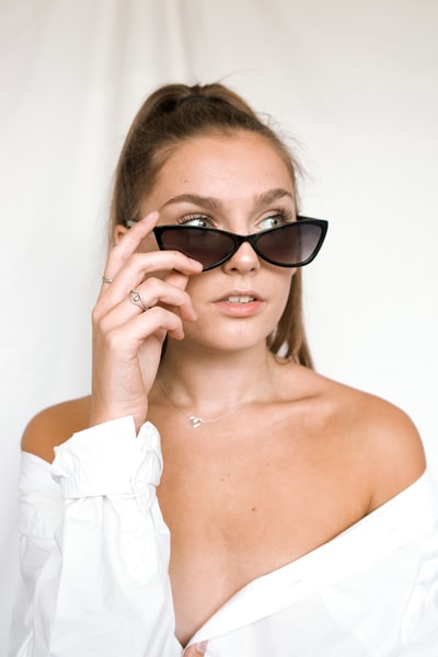 A woman in a white dew shoulder clothes wear dark sunglasses
